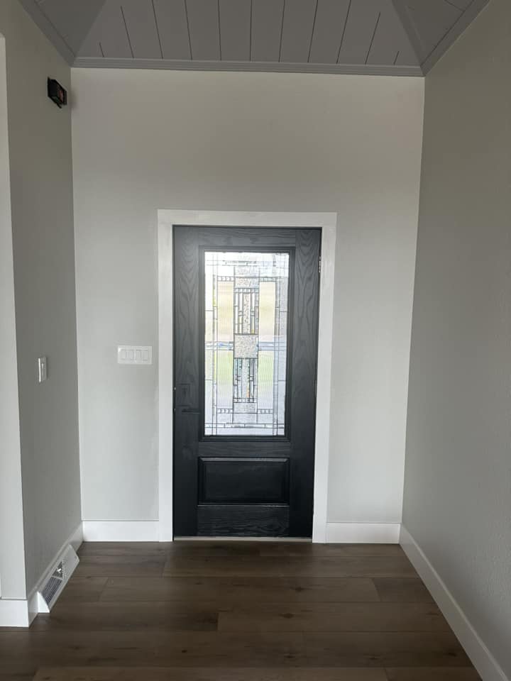 Finished entryway with dramatic black front door featuring stained-glass insert, shiplap ceiling, and dark hardwood floors